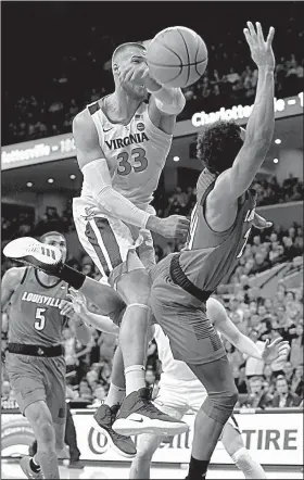  ?? AP/STEVE HELBER ?? Virginia center Jack Salt blocks a shot by Louisville guard Marco Anthony during the first half Saturday in Charlottes­ville, Va. No. 2 Virginia rallied for its eighth consecutiv­e victory, winning 73-68.