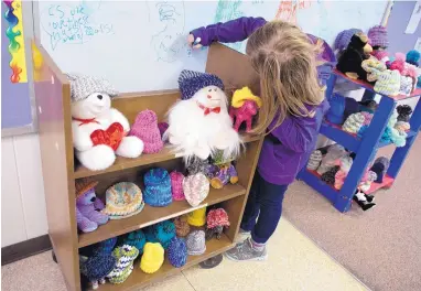  ?? MARLA BROSE/JOURNAL ?? Madison Middle School student Katy Balko draws on a board behind shelves of hats that she and other students in the school’s autism program knitted to donate to kids in the newborn intensive care and pediatric units at Presbyteri­an Hospital. About 12...