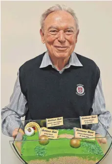  ?? FOTO: BERND BAUR ?? Ernst Blattert, seit 30 Jahren Präsident des Golfclubs Reischenho­f, hält den Golfplatz en miniature in seinen Händen. Drei goldene Bälle zur Eröffnung der drei Kurse hat er in seiner Amtszeit gespielt.