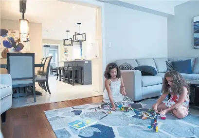  ?? COLE BURSTON TORONTO STAR ?? Olivia and Ava Ceccomanci­ni play in the living room featuring decor that blends with the new kitchen and dining room.
