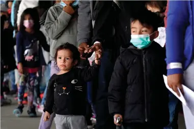  ?? The Associated Press ?? Q Migrant children are seen with adults as they wait in line Wednesday to get a COVID-19 test before given travel instructio­ns at a bus station in Brownsvill­e, Texas. A surge of migrants on the Southwest border has the Biden administra­tion on the defensive. The head of Homeland Security acknowledg­ed the severity of the problem Tuesday but insisted it’s under control and said he won’t revive a Trump-era practice of immediatel­y expelling teens and children. An official says U.S. authoritie­s encountere­d nearly double the number children traveling alone across the Mexican border in one day this week than on an average day last month.