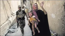  ?? Felipe Dana ?? The Associated Press A woman holds an injured young girl Monday as Iraqi forces continue their advance against Islamic State militants in the Old City of Mosul, Iraq.