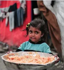  ?? AFP PHOTO ?? NEVER ENOUGH
A Palestinia­n girl holds a plate of rice outside her tent at a refugee camp in the Gaza Strip’s southernmo­st city of Rafah on Tuesday, Feb. 27, 2024.