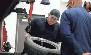  ??  ?? Trevor Stout checks a tire during the auto tech class. The nonprofit Impact60 sponsors the 10-week class, which meets twice a week.