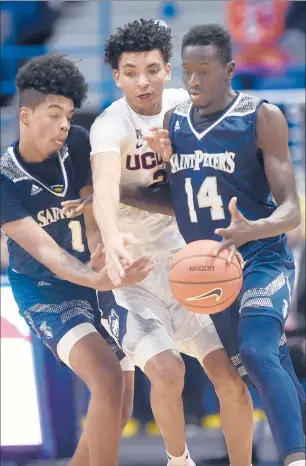  ?? BRAD HORRIGAN/HARTFORD COURANT ?? Huskies guard James Bouknight, center, tries to knock the ball away from St. Peter's forward Hassan Drame on Wednesday night at XL Center. At left is St. Peter's Peacocks guard Aaron Estrada.