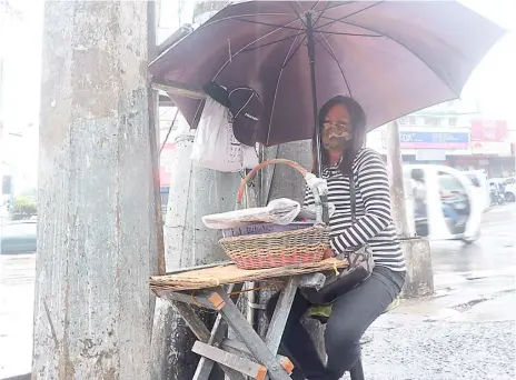  ?? PHOTOGRAPH COURTESY OF PNA ?? Perseveran­ce A solo mom of six sells candles and newspapers at the corner of EDSA and Kamuning road in Quezon City notwithsta­nding the elements just to be able to feed her children at this time of the pandemic.