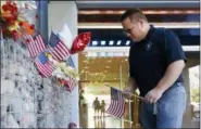  ?? ROSS D. FRANKLIN — THE ASSOCIATED PRESS ?? Ted Olsen, of Phoenix, looks to place an American flag at a makeshift memorial in honor of the late Arizona Republican Sen. John McCain at McCain’s office Monday in Phoenix.