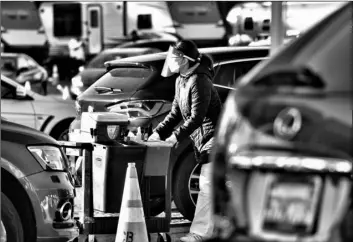  ?? AP Photo/Richard Vogel ?? A health care worker gets ready to distribute the COVID-19 vaccine to residents waiting in their cars in the early morning at Dodger Stadium, on Tuesday Los Angeles.