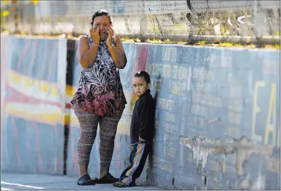  ?? Damian Dovarganes ?? The Associated Press Mother Elizabeth Acevedo and her son, Andres, 3, wait Thursday for news about her son, Jose, an eighth-grade student, after a school shooting in Los Angeles. A 12-year-old girl was booked on suspicion of negligent discharge of a...