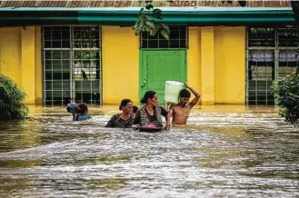  ?? Ferdinandh Cabrera / AFP / Getty Images ?? Residents evacuate to a safer place in Kabacan, North Cotabato, on the southern island of Mindanao in the Philippine­s. A tropical storm arrived late Thursday and is expected to blow out of the country by Monday. The Philippine­s is hit by an average of...