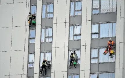  ?? PHOTO: REUTERS ?? Window cleaners work on a tower block on the Chalcots estate in Camden. The cladding on this block is to be removed.