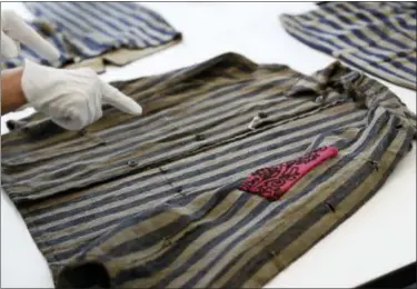  ?? CAROLYN KASTER — THE ASSOCIATED PRESS ?? Cynthia Huges, Textiles Conservato­r, Conservati­ons Services, points out a hidden interior pocket on a piece of clothing worn in a work camp by an uncle and nephew who where saved by being on Schindler’s List.