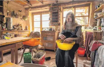  ?? FOTO: HARALD TITTEL/DPA ?? Friedmunt Sonnemann sitzt in der Küche seines Lehmhauses und streicht Samen aus getrocknet­er Nachtkerze in eine Schüssel. Er sieht sich nicht als Aussteiger, sondern eher als Lebensküns­tler.