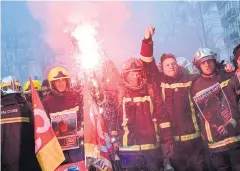  ?? AFP ?? Men dressed in firefighte­r uniforms wave flags of the French trade union General Confederat­ion of Labour and burn flares at a demonstrat­ion in Paris.