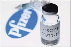  ?? JOEL SAGET / AFP via Getty Images ?? This illustrati­on picture taken in Paris on Nov. 23 shows a syringe and a bottle reading "Covid-19 Vaccine" next to the Pfizer company logo.