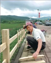  ?? ZHENG JINRAN / CHINA DAILY ?? Workers build a fence around a large field of flowers last month at the Xishui Forest Farm in Yichun, Heilongjia­ng province, in preparatio­n for an expected flood of tourists.