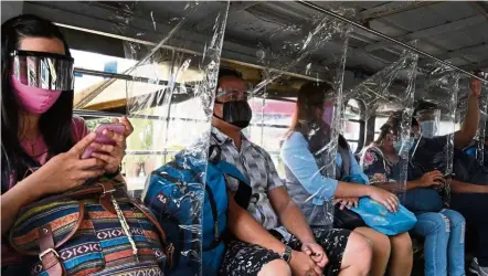  ?? — AFP ?? A screen away: Passengers wearing face shields sitting in a jeepney separated by plastic dividers as part of health protocols imposed by authoritie­s against the Covid-19 pandemic in Manila.