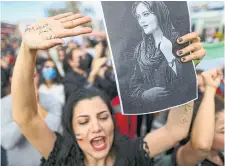  ?? E MRAH GUREL THE ASSOCIATED PRESS ?? A protester holds up a drawing of Mahsa Amini, who died while in the custody of Iran’s morality police. They had detained Amini for alleged violations of the country’s strict Islamic dress code.