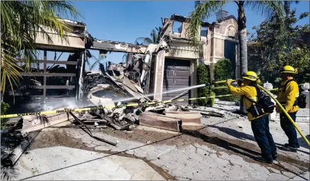  ?? ?? Firefighte­rs put out hot spots Thursday at a house in the hilltop neighborho­od on Coronado Pointe. Most of the 20homes lost in the Coastal fire were on Coronado Pointe. The fire was reported just before 2:45p.m. Wednesday in Aliso Woods Canyon and quickly moved up steep terrain.
Richard and Sandy Vogel embrace outside their destroyed home on Coronado Pointe after the Coastal fire burned it down on Wednesday. The pair made a narrow escape.