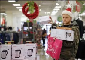  ?? ELAINE THOMPSON — THE ASSOCIATED PRESS ?? Joey Ellis adds to his armful of items while shopping for deals at a J.C. Penney store Friday in Seattle. Black Friday has morphed from a single day when people got up early to score doorbuster­s into a whole season of deals, so shoppers may feel less...