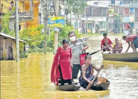  ??  ?? Locals using boats to cross a waterlogge­d street due to a flood following the overflow of the Shilaboty river and the Kangshabot­i river, in West Bengal’s Ghatal on Monday.