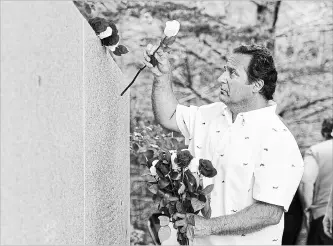  ?? ANDREW VAUGHAN THE CANADIAN PRESS ?? Stephen Thompson, from Atlanta, Ga., places roses as he remembers his father Ernest Thompson, who died in the crash of Swissair Flight 111 Sept. 2, 1998, at a memorial service at Bayswater Beach, N.S. on Sunday.