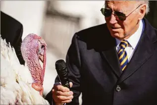  ?? Andrew Harnik / Associated Press ?? President Joe Biden holds the microphone to Chocolate, the national Thanksgivi­ng turkey, during a pardoning ceremony at the White House on Monday.