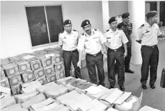  ??  ?? Romli (second left) showing the seized cooking oil at MMEA detention hall in Tawau.