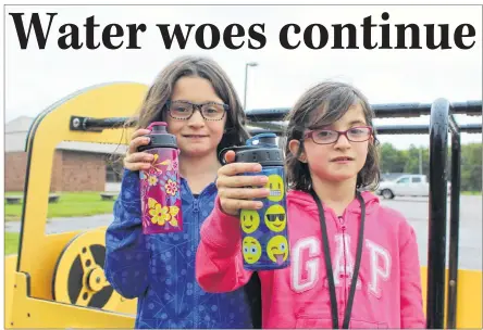  ?? COLIN MACLEAN/JOURNAL PIONEER ?? Liv, left, and Abi Bulman, show off their water bottles outside their school, Somerset Elementary School in Kinkora. Staff and students at the school will have to drink bottled water for a while, until Public School’s Branch finds a way to fix the ongoing water quality issues at the school.