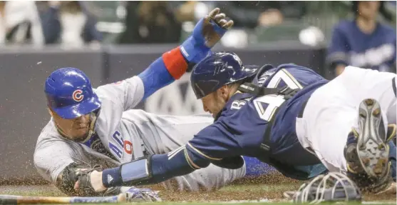  ?? TOM LYNN/ AP ?? Cubs second baseman Javy Baez avoids the tag of Brewers catcher Jett Bandy to score during the second inning, giving the Cubs a 3- 0 lead Thursday in Milwaukee.