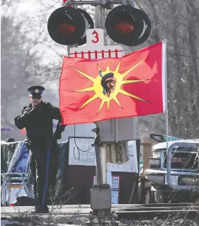 ?? ADRIAN WYLD / THE CANADIAN PRESS ?? An Ontario Provincial Police officer talks on a radio after arrests were made at a rail blockade in Tyendinaga Mohawk Territory, near Belleville, Ont., on Monday.