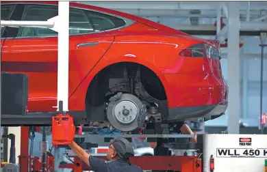  ?? BLOOMBERG ?? An employee fits a rear axle to a Tesla Model S automobile on the driving unit assembly line at the Tesla Inc factory in Tilburg, the Netherland­s.