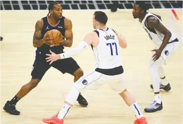  ?? HARRY HOW / GETTY IMAGES ?? Kawhi Leonard of the L.A. Clippers, left, looks to pass out of a double team by the
Dallas Mavericks during Game 2 of the Western Conference first round series.