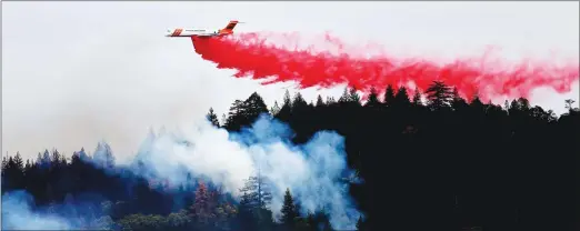  ?? Associated Press ?? A firefighti­ng plane drops a load of fire retardant over a smoldering hillside on Tuesday in Middletown. The fire that sped through Middletown and other parts of rural Lake County, less than 100 miles north of San Francisco, has continued to burn since...