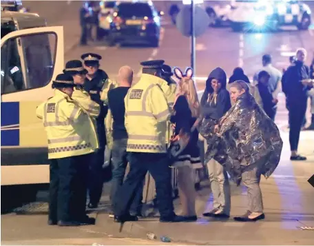  ?? RUI VIEIRA/ AP PETER BYRNE/ PA VIA AP ?? Police block a road near the Manchester Arena in central Manchester, England, early Tuesday. Britain’s terror level has been set at “severe” in recent years. THE SCENE Emergency services personnel speak to people outside Manchester Arena Monday after...