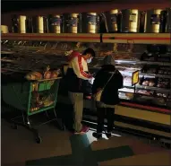  ?? LM OTERO — THE ASSOCIATED PRESS ?? Customers use the light from a cell phone to look in the meat section of a grocery store Feb. 16, in Dallas. Even though the store lost power, it was open for cash only sales.