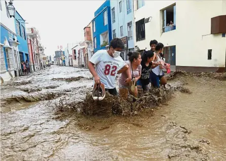  ??  ?? To safer grounds: Residents wading through the water as a flash flood hits the city of Trujillo, 570km north of Lima in Peru. — AFP