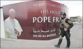  ??  ?? Un elemento de seguridad de una división especial hace guardia junto a un cartel con la imagen del papa Francisco en Bagdad