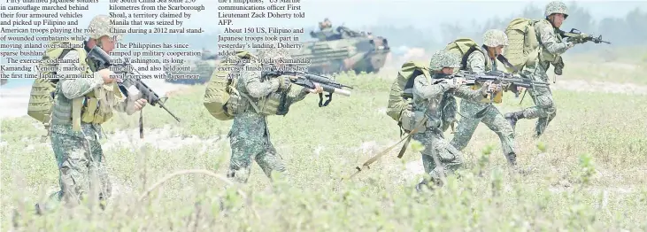  ?? — AFP photos ?? Philippine marines take position next to US marines Amphibious Assault Vehicles (AAV) during an amphibious landing exercise at the beach of the Philippine navy training center facing the south China sea in San Antonio town, Zambales province, north of Manila.