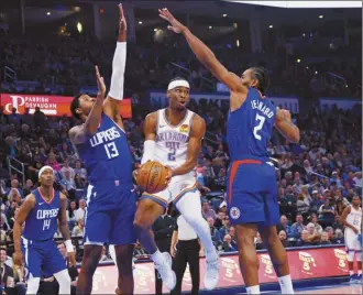  ?? AP photo ?? Thunder guard Shai Gilgeous-Alexander (center) looks to pass between Clippers forwards Paul George (left) and Kawhi Leonard during the first half of Oklahoma City’s 129-107 victory over Los Angeles on Thursday.