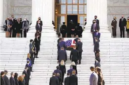  ?? J. SCOTT APPLEWHITE AP ?? Justice Ruth Bader Ginsburg’s coffin is carried up the court’s grand marble steps by the Supreme Court police, flanked by lines of the justice’s former law clerks.