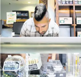  ?? AP ?? In this June 27, 2017 file photo, Jerred Kiloh, owner of the licensed medical marijuana dispensary Higher Path, stocks shelves with cannabis products in Los Angeles.