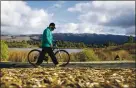  ?? ANDA CHU – STAFF PHOTOGRAPH­ER ?? Gonzo Gonzalez of San Jose walks his bike along a path at Lake Cunningham Park in San Jose on Saturday.