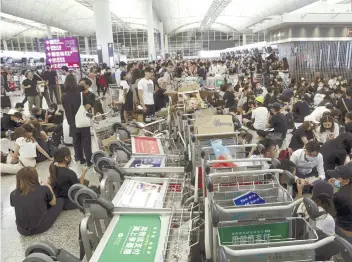  ?? AP FOTO ?? UNREST. Protesters use luggage trolleys to block the walkway to the departure gates during a demonstrat­ion at the Hong Kong Internatio­nal Airport on Aug. 13, 2019.