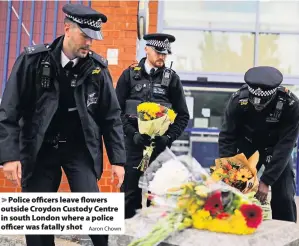  ?? Aaron Chown ?? Police officers leave flowers outside Croydon Custody Centre in south London where a police officer was fatally shot