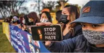  ?? Apu Gomes / AFP via Getty Images ?? Julie Tran holds up a message for the country while attending a vigil in Garden Grove, Calif., to unite against recent violence.