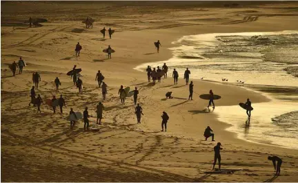  ??  ?? Surfers and swimmers head to the ocean after Bondi Beach reopened following a five week closure in Sydney on Tuesday, amid the COVID-19 novel coronaviru­s pandemic.—AFP photos