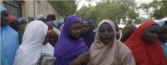  ?? AP ?? PRAYERS ANSWERED: Family members of schoolboys taken hostage by Boko Haram in Nigeria await a reunion Friday in Katsina, Nigeria. More than 300 boys were kidnapped in an attack on their school last week.