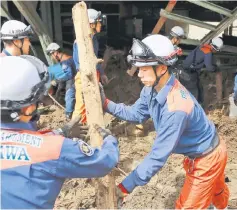  ??  ?? Fire department officers remove debris from a damaged house in a flooded area in Asakura. — AFP photo