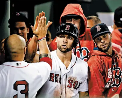  ?? ADAM GLANZMAN/GETTY ?? Providence graduate Sam Travis, center, gets congratula­ted after scoring a run for the Red Sox during a game against the Rangers in 2017.